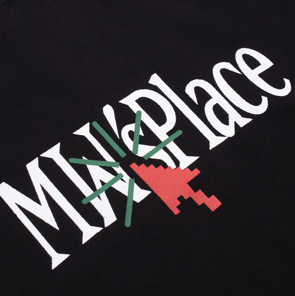 Detailed macro perspective of the chest screen print on the black Metalwood Studio MW Place T-Shirt, highlighting the sharp white serifs of the "MW Place" lettering accented by a digital red pixel arrow cursor and radiate green burst lines on smooth black cotton fabric.