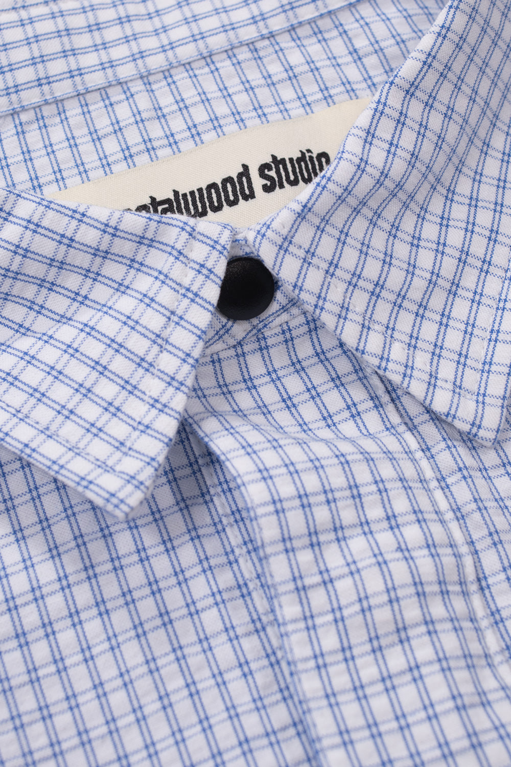 Close-up of Metalwood Studio Plaid Tactical Overshirt collar featuring crisp white blue plaid fabric, premium snap-button fastening and high-quality cotton craftsmanship