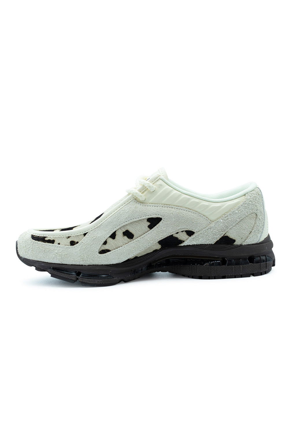Medial arch profile view of the New Balance 1890A shoe, highlighting the continuous cow print pony hair underlay through side cut-outs, textured hairy suede chassis, ribbed leather eyestay collar panel, and the performance-driven black ABZORB foam midsole with grooved rubber outsole.