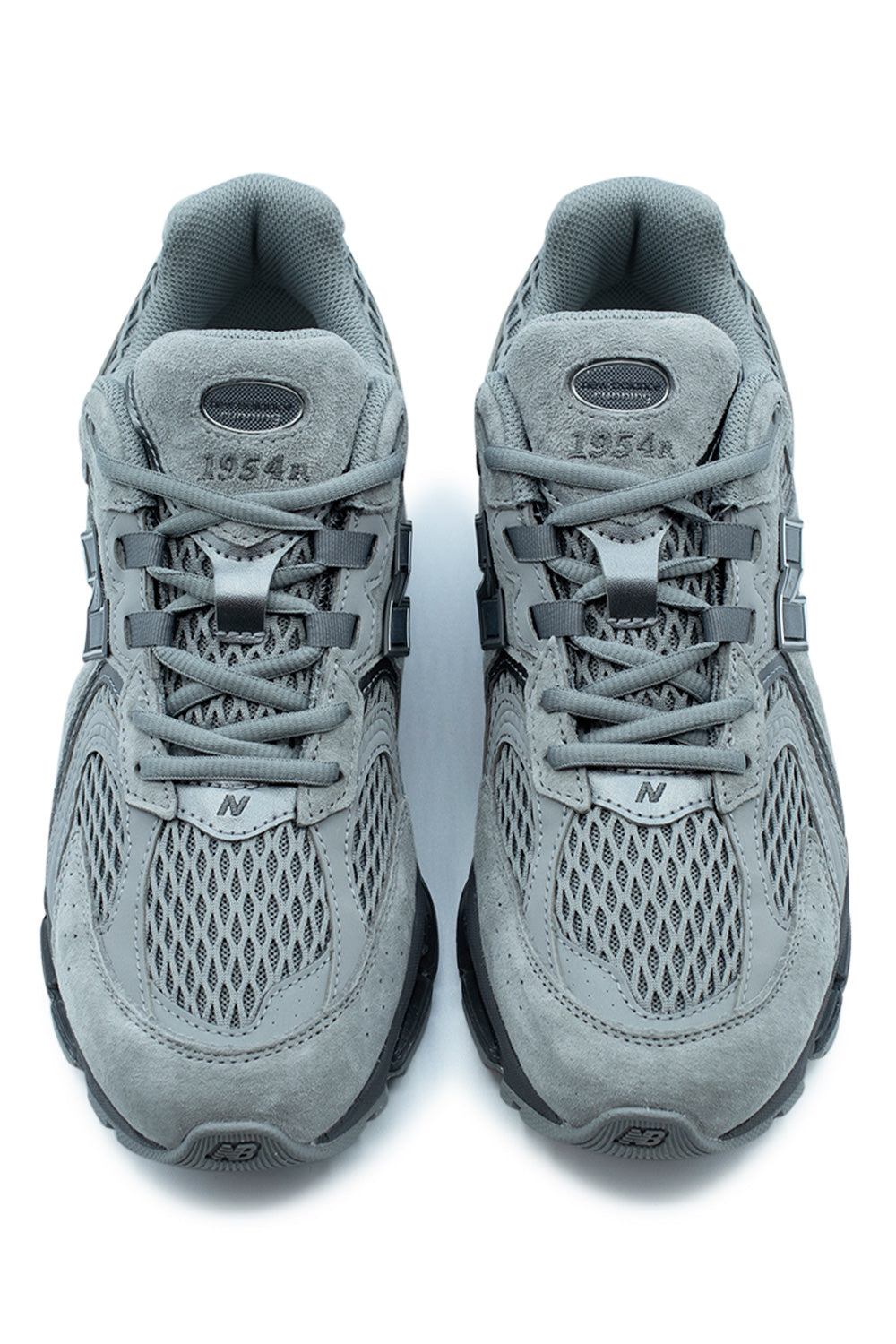 Top-down view of a pair of slate grey New Balance 1954R shoes, highlighting the matching grey laces, coarse mesh toe box, and oval 1954R tongue branding.