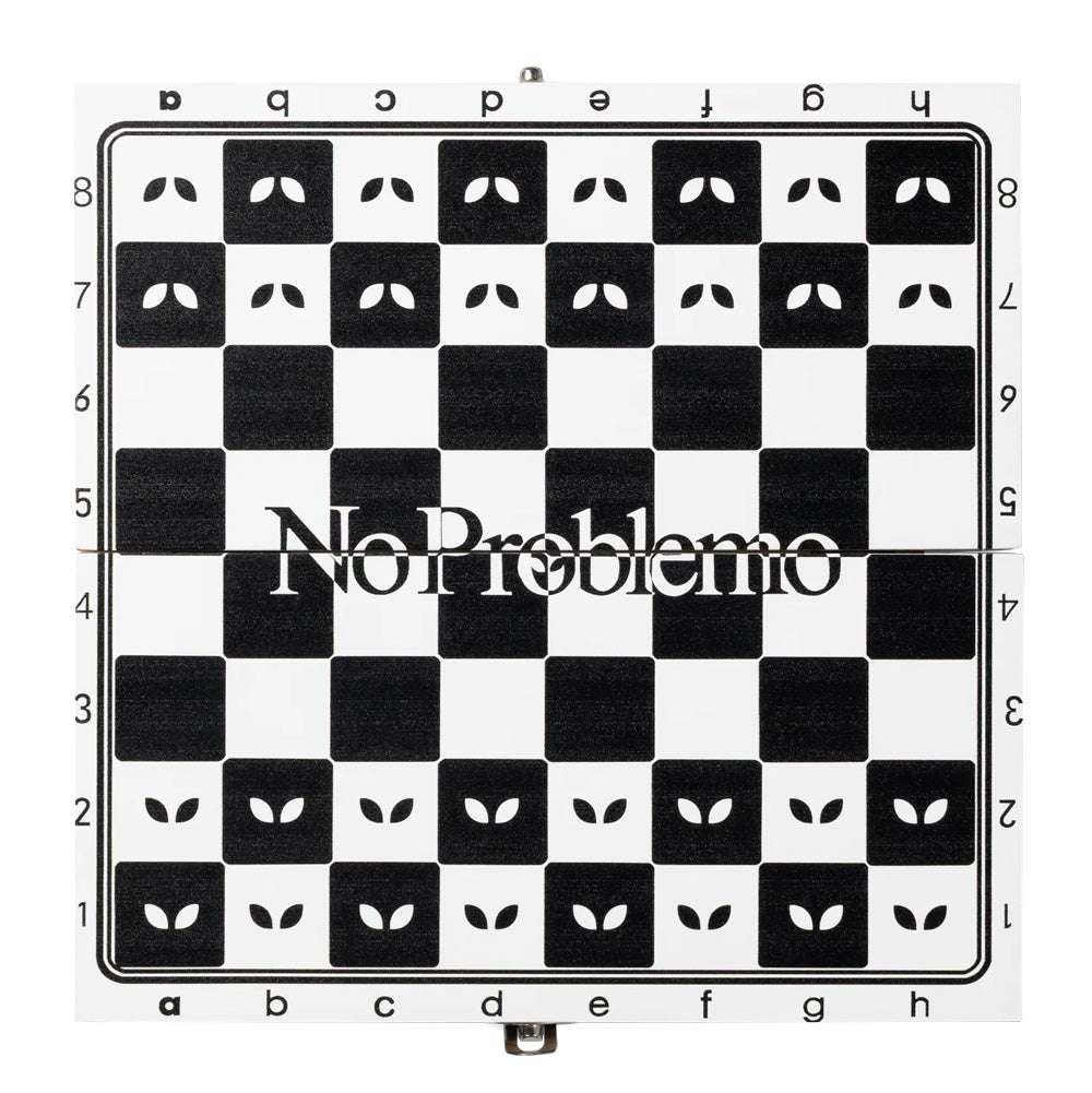 Top-down flat lay studio view of the fully unfolded square Aries No Problemo chess board, detailing the black-and-white grid pattern featuring stylized Aries alien eyes printed inside the starting rank squares, algebraic notation along the edges, and the centered "No Problemo" brand typography spanning across rows four and five.