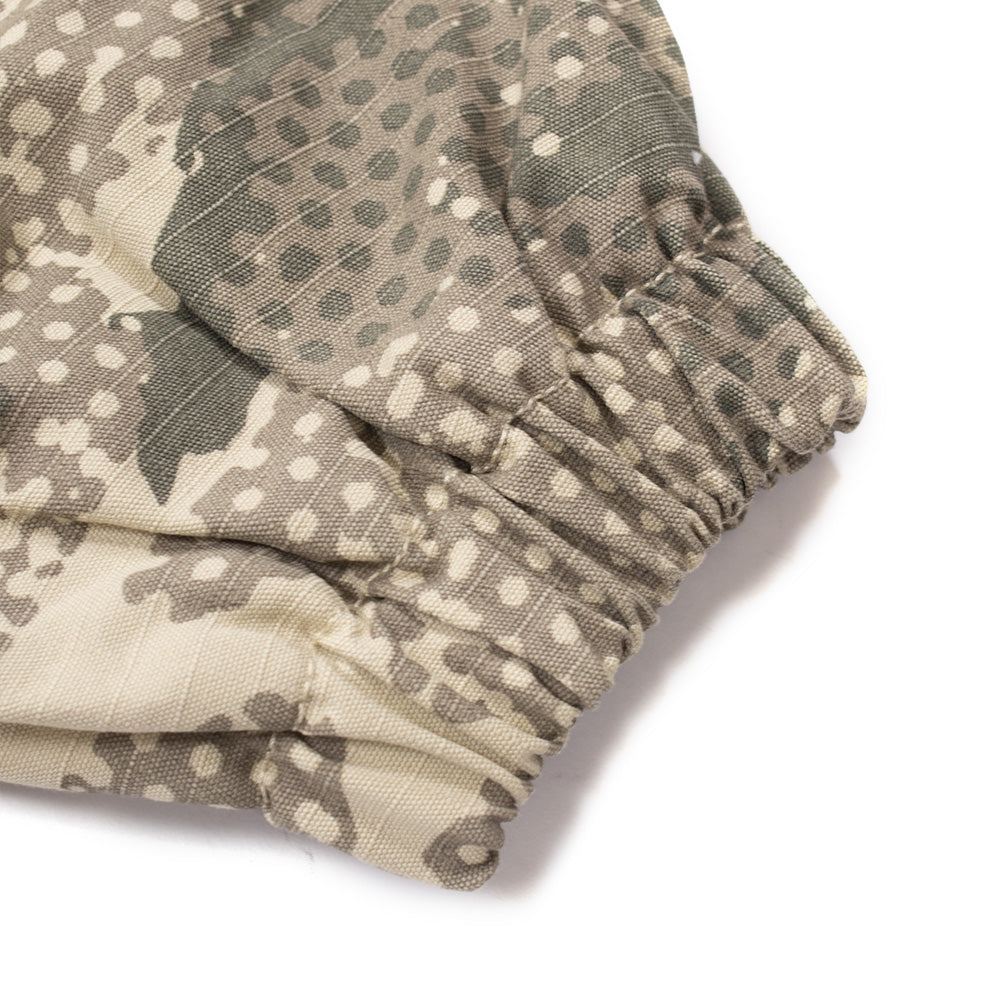 Macro studio view of the sleeve cuff on the No Problemo Forest Ripstop Work Jacket in Sand, focusing on the gathered elastic wrist trim, double-needle edge stitching, and the textured crosshatch weave of the heavy cotton ripstop camouflage shell.
