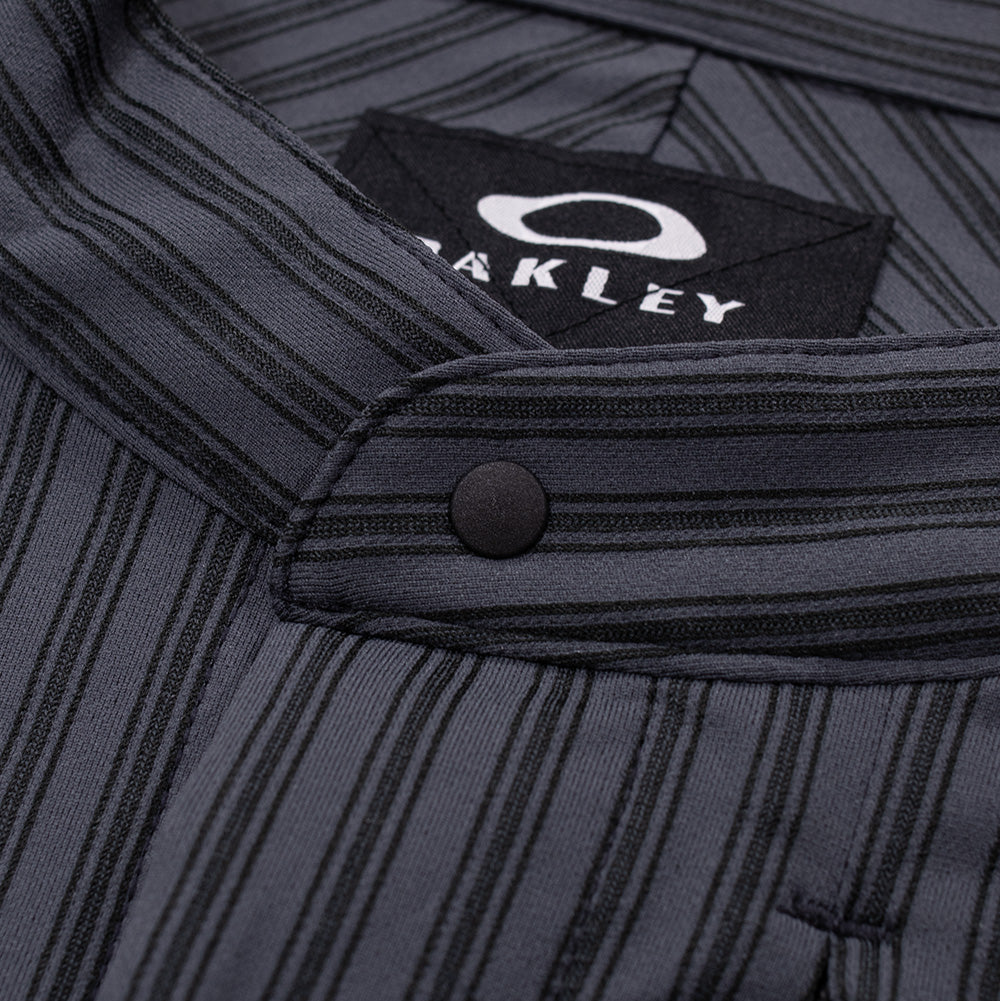 Macro studio close-up of the mandarin band collar and top neckline closure on the Oakley FGL Fuel LS Shirt, displaying the clean horizontal stripe alignment on the stand collar, matte black rounded snap fastener, and woven black Oakley neck label.