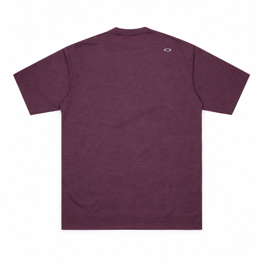 Back flat lay studio perspective of the Oakley FGL Scratch SS Tee 6.7 in Rouge, highlighting the clean shoulder lines, straight cut hem, finely textured heathered red-plum fabric drape, and a small heat-sealed metallic silver Oakley Ellipse logo centered beneath the rear neckband.
