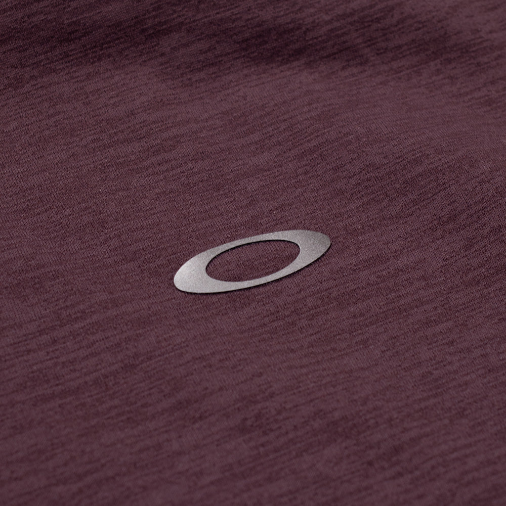 Extreme macro close-up of the back neck detailing on the Oakley FGL Scratch SS Tee, featuring the clean reflective silver heat-transfer Oakley Ellipse emblem cleanly bonded onto the fine melange knit structure of the heathered red technical fabric.