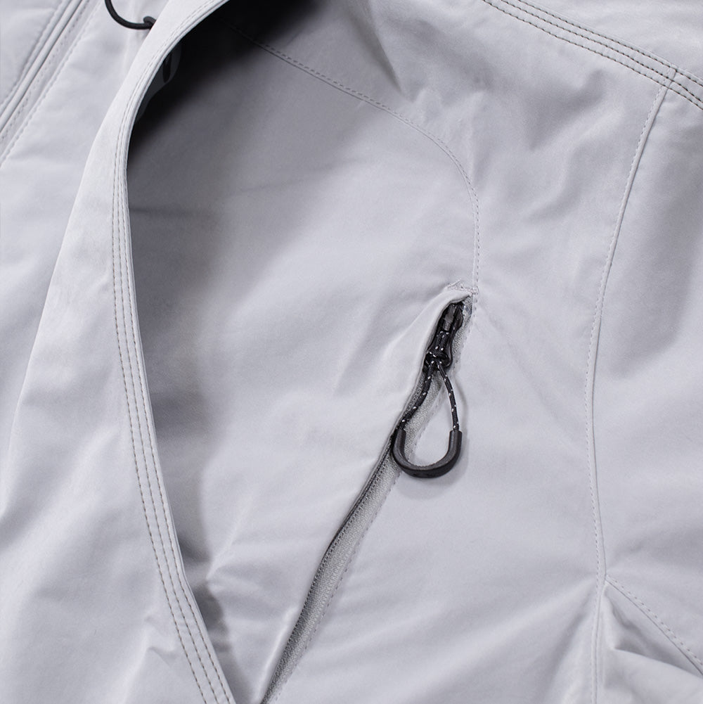 Macro view of the multi-entry utility pocket setup on the Oakley FGL Sector Jacket, highlighting the curved pocket flap opening with reinforced edge stitching and an exposed vertical reverse-coil zipper equipped with a black paracord pull tab and contoured rubber grip.