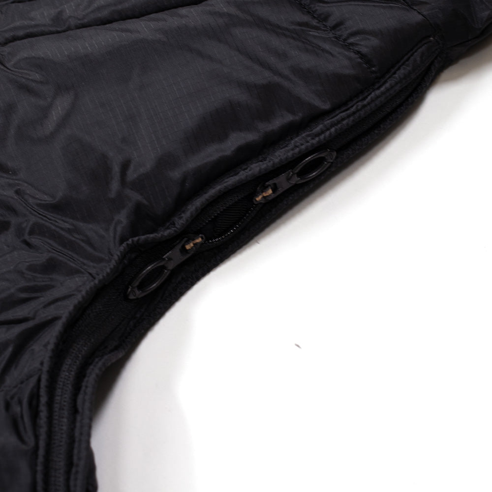 Detailed macro studio view of the underarm pit-zip ventilation system on the Oakley FGL Stealth Ins Jacket 2.0 in Stealth Black, showcasing the two-way zipper track with dual contoured black ring pullers built into the seam of the water-repellent, quilted black Schoeller micro-ripstop technical shell fabric.