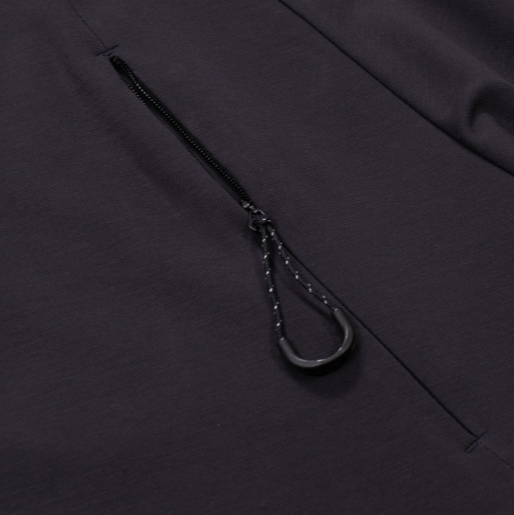 Detailed macro perspective of the chest pocket on the Oakley FGL Union SS Tee, capturing the discreet concealed zipper mechanism integrated into the ergonomic front panel seam, complete with a speckled black utility paracord puller and textured plastic grip.