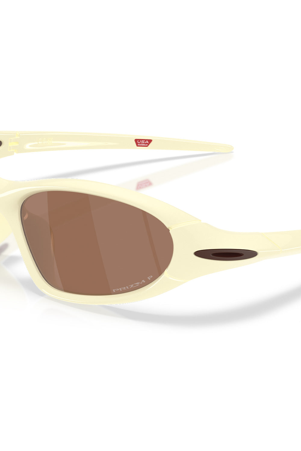 Macro close-up shot of the left lens and temple hinge on the Oakley Portal Jacket Cream sunglasses, highlighting the bronze Prizm P polarized lens engraving and metallic dark ellipse logo.