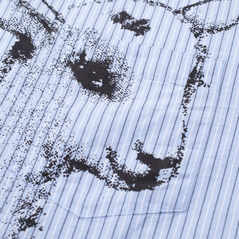 Detailed close-up shot of the left chest pocket on the Obey Billy Woven Shirt, focusing on the seamless alignment of the lamb face print continuing from the shirt body onto the patch pocket face over the pinstriped background.