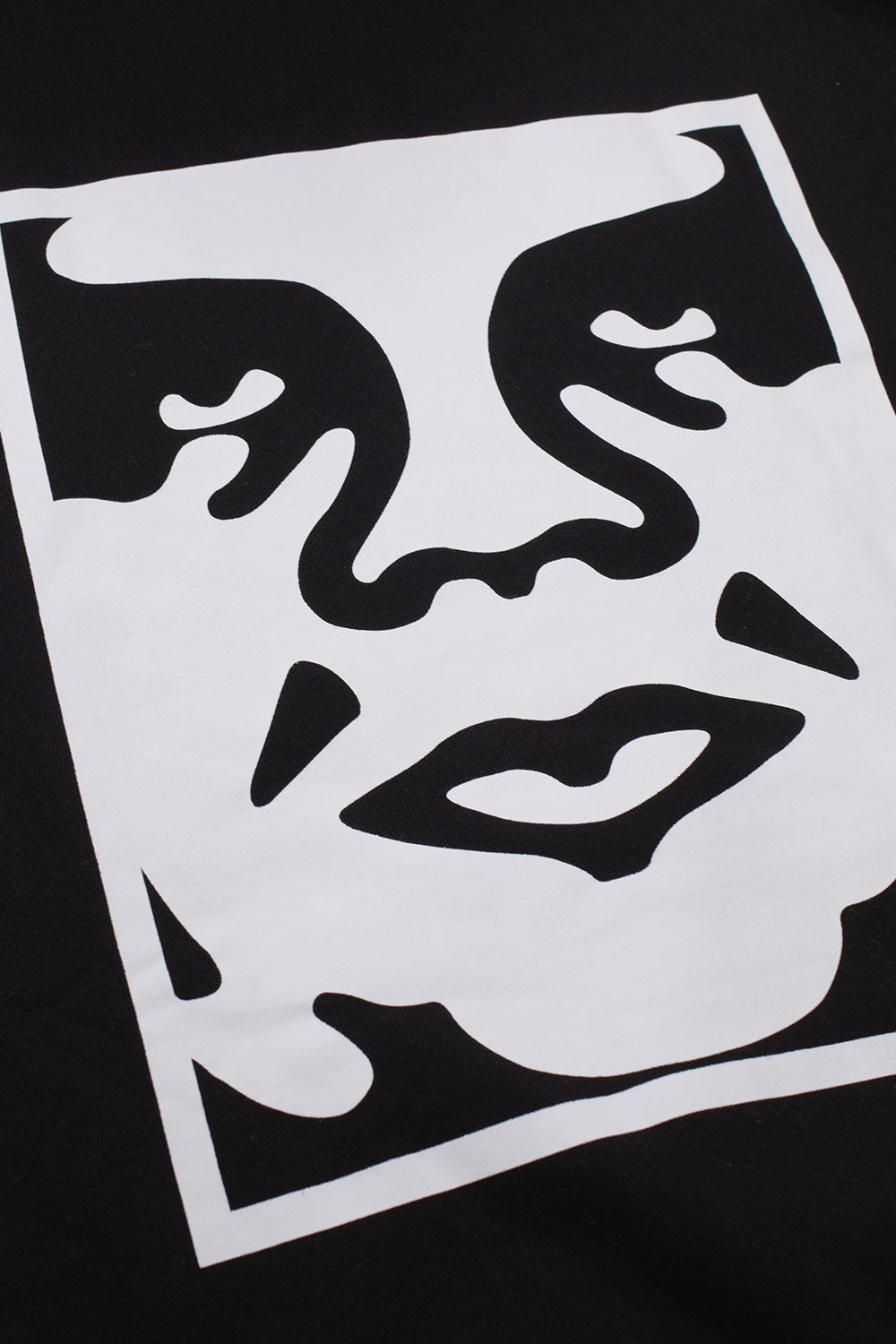 Close-up detail shot of the oversized white Shepard Fairey Giant face icon screen print on the back of the black heavy fleece Obey Bold Icon hoodie.