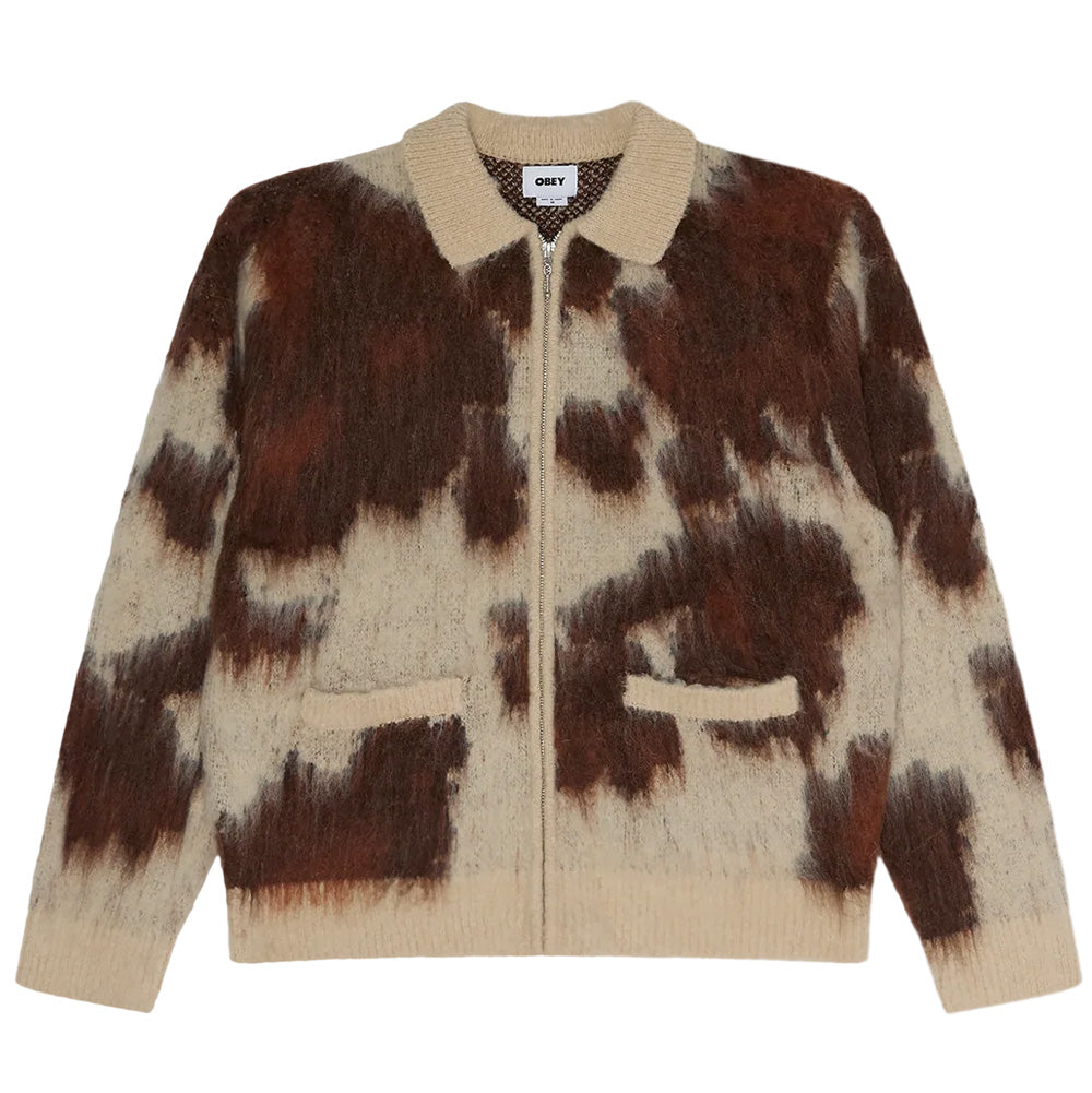 Front flat lay view of the Obey Cow Pattern Zip Sweater, showcasing a relaxed-fit knit cardigan crafted from a brushed, fuzzy mohair-blend yarn with an organic cowhide print in rich brown and off-white tones, featuring a solid cream ribbed spread polo collar, full-length silver zip closure, horizontal welt hand pockets, and matching ribbed knit cuffs and hem.