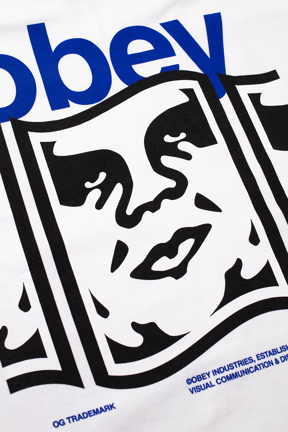 Detailed close-up shot of the backprint on the white Obey Disruption tee, highlighting the bold royal blue font lettering, distorted black and white André the Giant sticker face graphics, and crisp OG Trademark subtext.