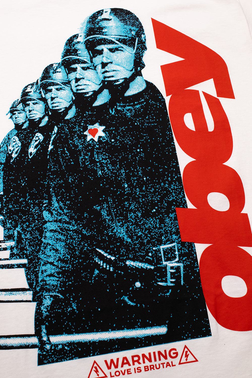 Detailed close-up shot of the front graphic on the vintage white Obey tee, highlighting the grainy blue halftone print of helmeted police officers holding batons, the heart badge detail, and bold red Obey branding alongside the Warning Love Is Brutal hazard sign.