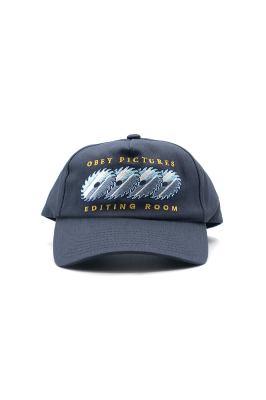 Front view of the navy blue Obey Pictures 5 Panel Snapback Cap, crafted from 100% cotton twill, showcasing a slightly curved brim, top button, and detailed multicolored embroidery on the front panel featuring repeating circular saw blades flanked by golden-yellow arched Obey Pictures and Editing Room typography.