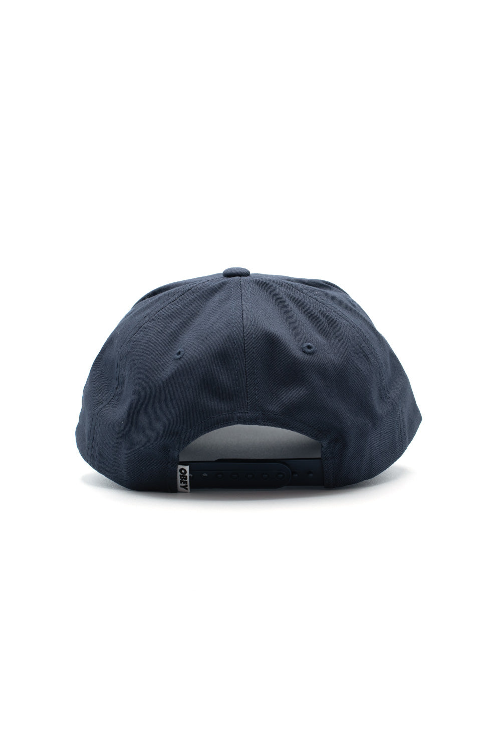 Rear view of the Obey Pictures 5 Panel Snapback in dark navy, highlighting the semi-circular cut-out opening, tonal plastic snapback click closure, embroidered ventilation eyelets, and a white woven Obey flag label stitched onto the left side of the closure strap.