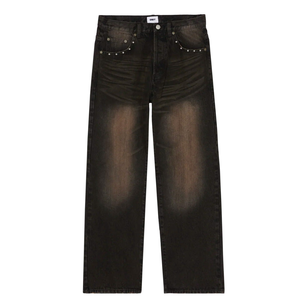 Front flat lay view of the Obey Studded Boxcar Straight Leg Denim in black rust wash, showcasing a relaxed straight-leg skate cut in heavy cotton denim featuring pronounced vintage whiskering and gradient copper-brown fade across the thighs and knees, a button-fly waist with belt loops, and curved front hand pocket scoops accented with an arched row of antique silver round domed metal studs.