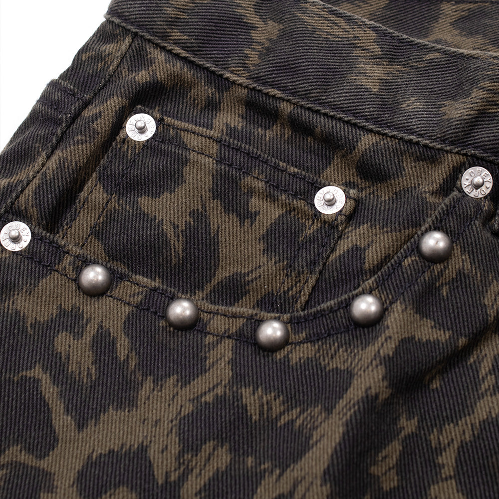 Detailed close-up shot of the front right pocket scoop on the Obey Studded Boxcar Denim in Dark Leopard, focusing on the nested coin pocket secured by branded silver metal rivets and the curving contour line of raised metallic dome studs along the leopard-printed twill pocket hem.