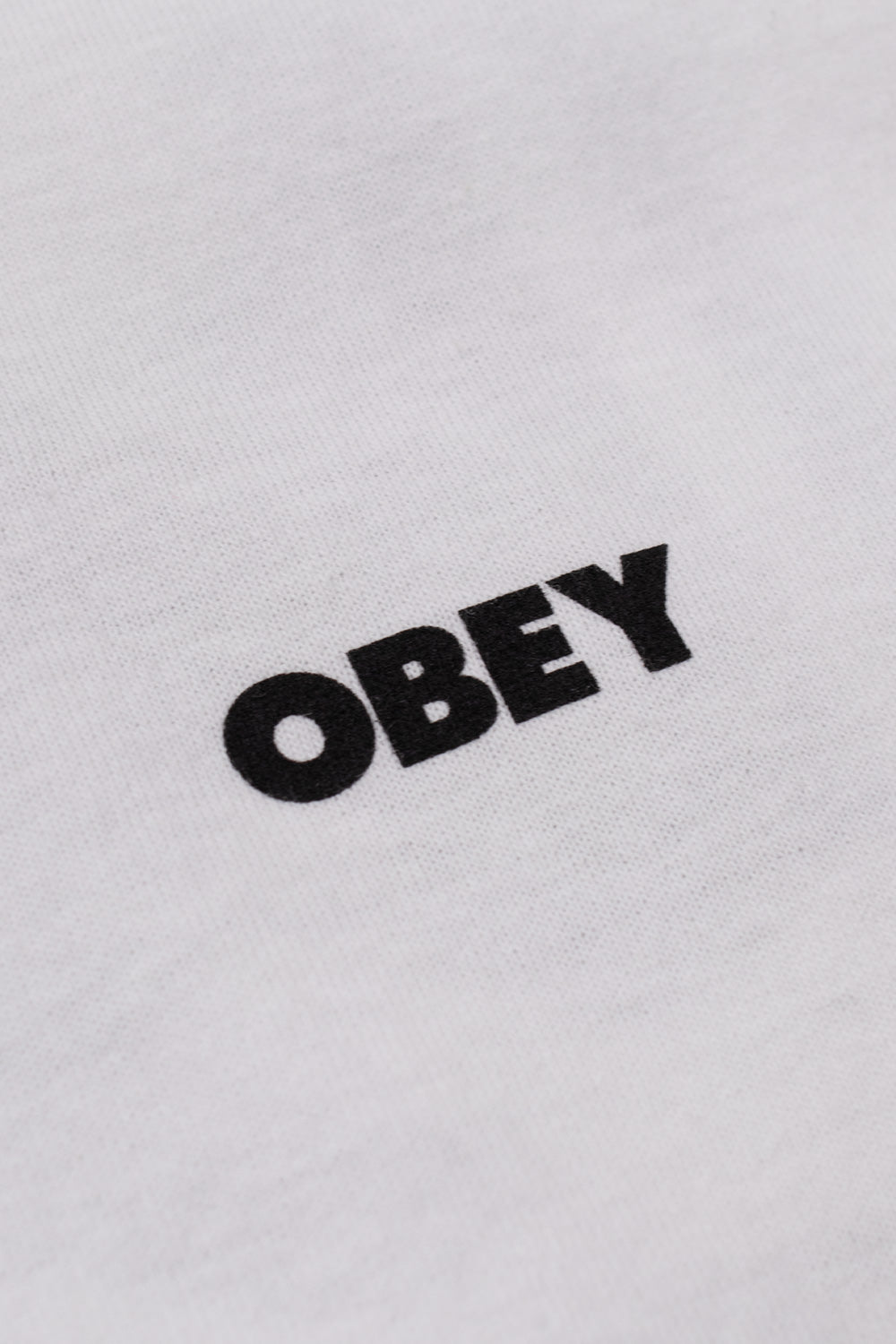Close-up detail shot of the black screen-printed back graphic on the white Obey tee, highlighting the iconic framed Giant Eyes artwork, Obey Worldwide typography, and listed cities.