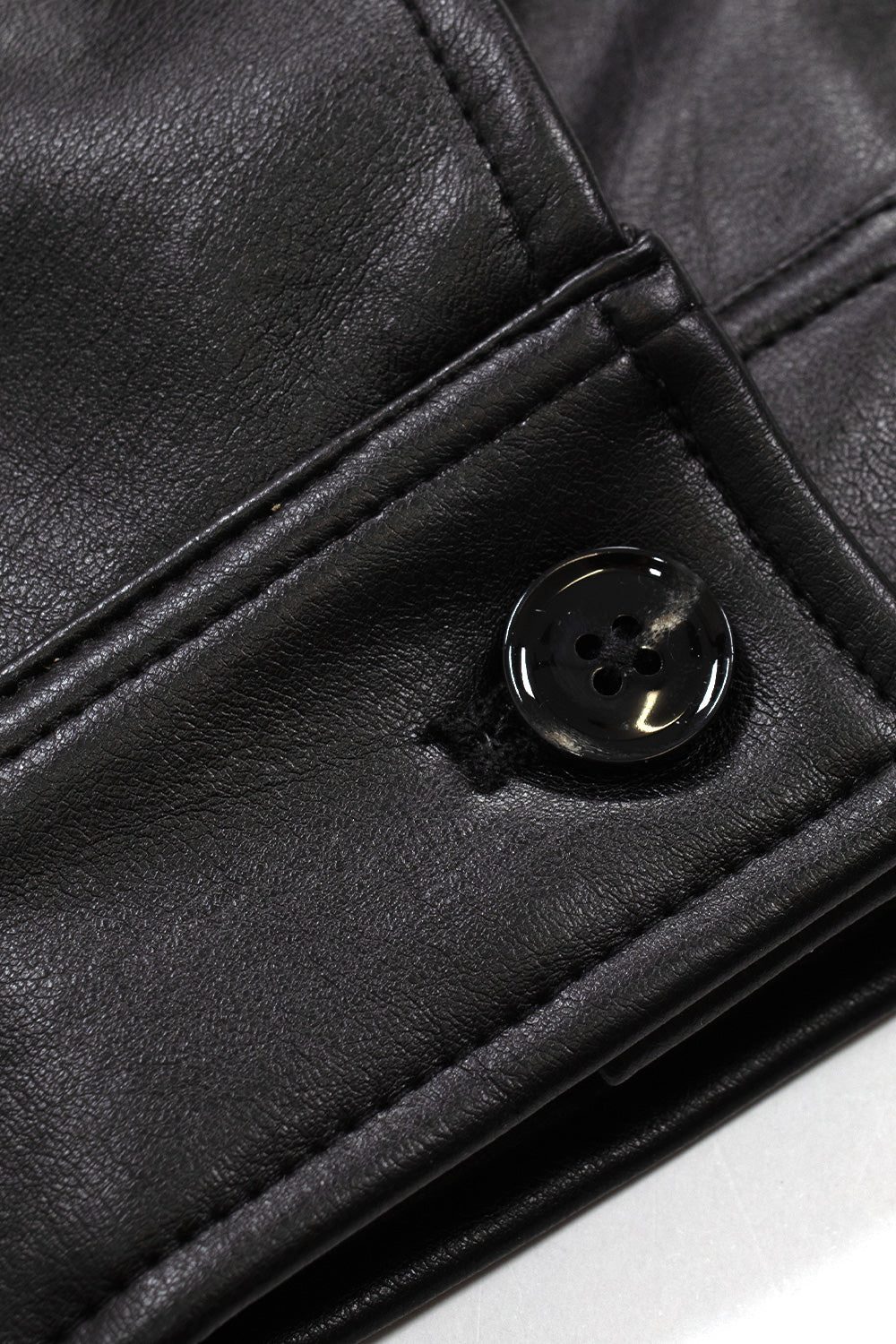 Macro detail shot of the adjustable sleeve cuff on the Obey Workman PU Jacket, showing the black faux leather paneling, tonal heavy-duty topstitching, and a glossy black four-hole button closure.