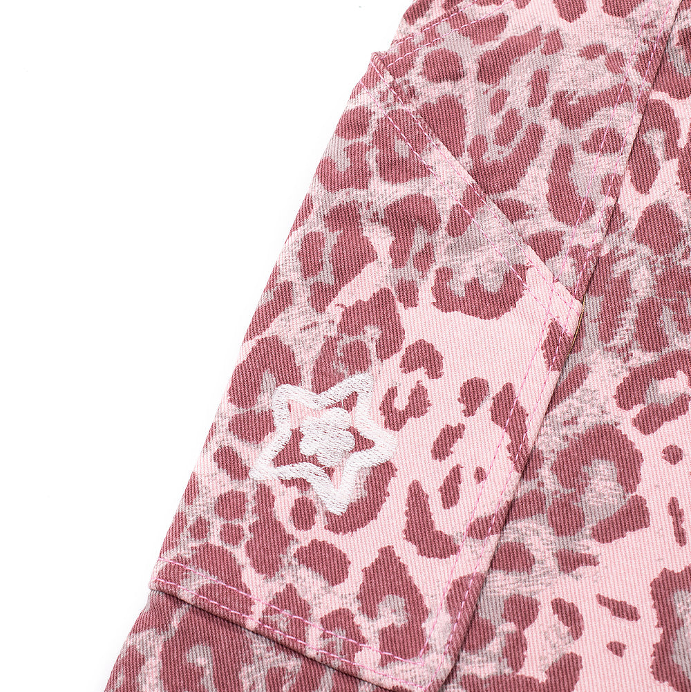 Macro perspective of the right thigh carpenter utility tool pocket on the Starteam Leopard Star Jeans, highlighting the angled opening seam, reinforced side edge construction, and a compact white embroidered Starteam flower-star motif centered on the vibrant pink patterned cotton twill.