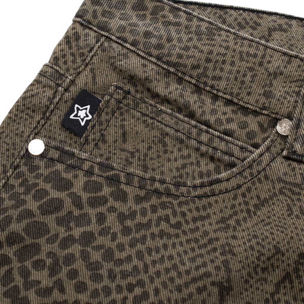 Macro studio view of the right front coin pocket on the olive Starteam East Village Snakeskin Jeans, detailing the silver-finished metal edge rivets, clean double-track stitching, and a small woven black tag embroidered with a crisp white star logo nestled against the scaly reptile print denim.