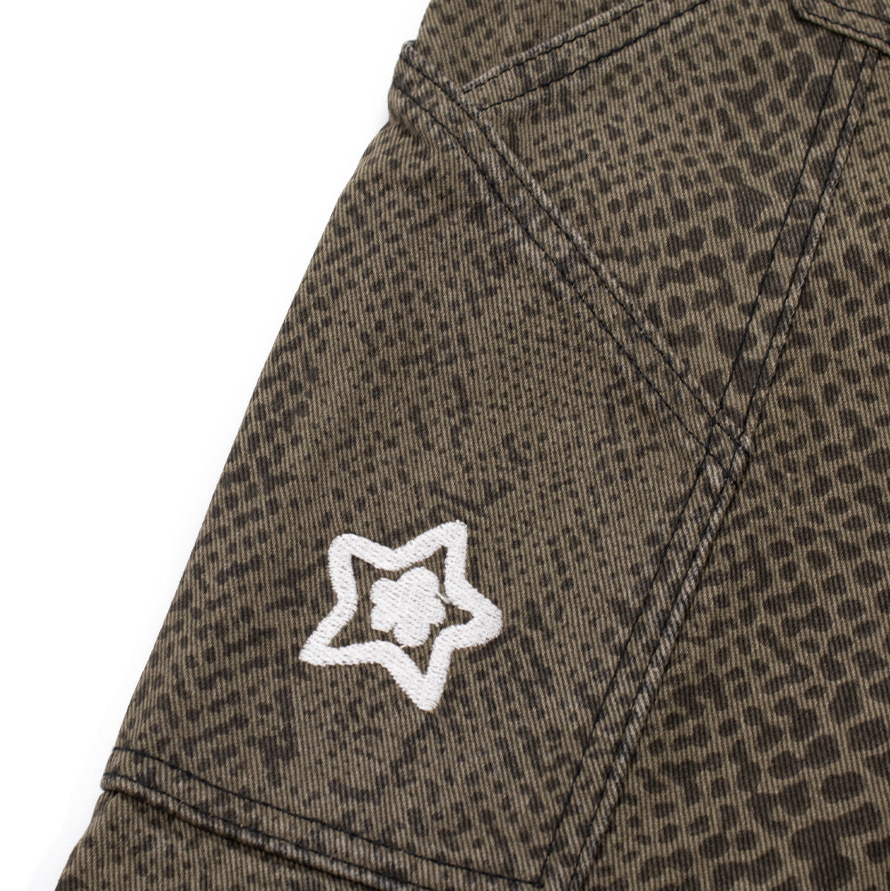 Macro perspective of the right thigh carpenter tool pocket on the Starteam Snakeskin Star Jeans, highlighting the angled pocket top, reinforced utility side seam, and a miniature white embroidered Starteam flower-star emblem centered directly on the snakeskin-printed cotton twill.