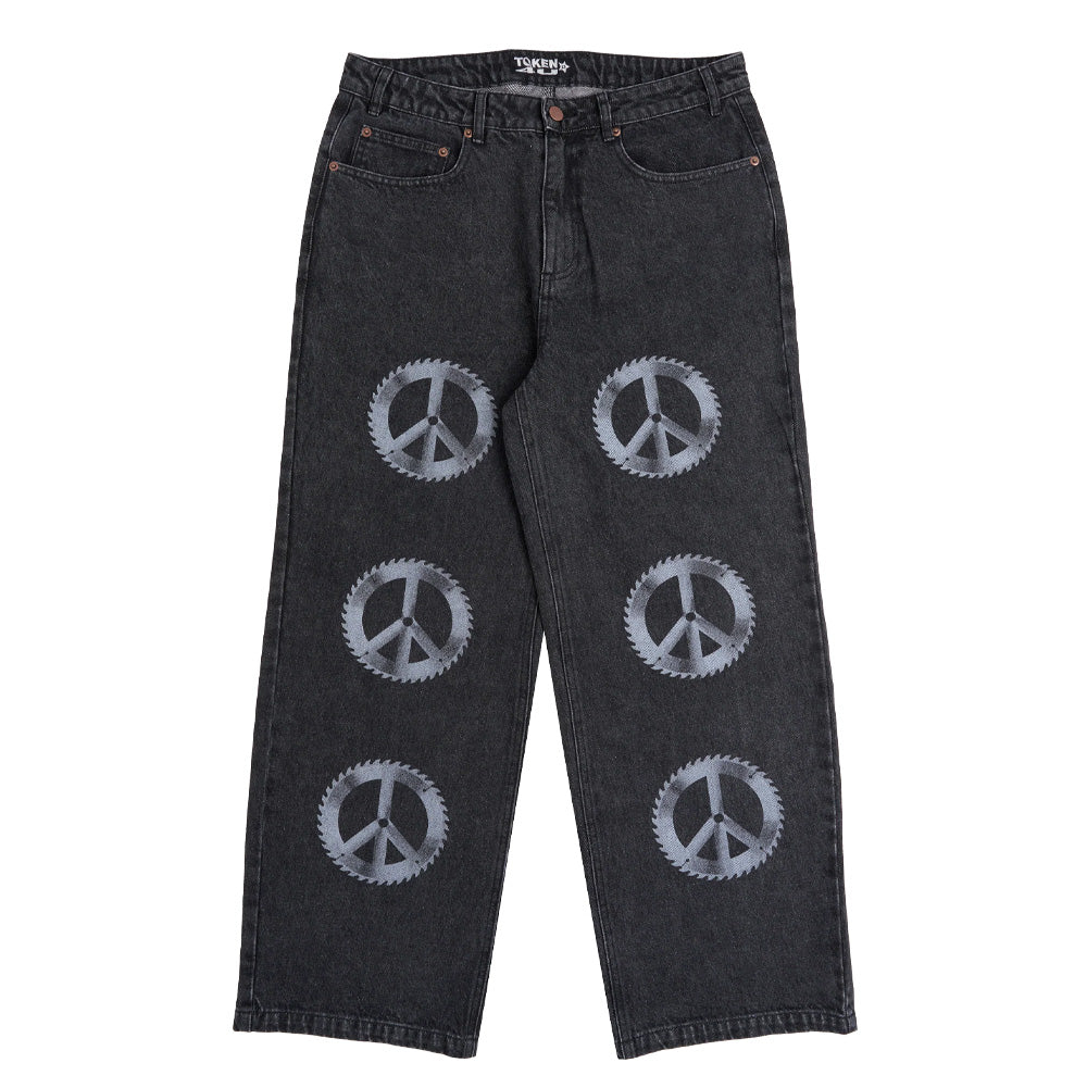 Front flat lay view of the Token Alphabet Jeans in off-black acid wash denim, showcasing a baggy wide-leg skate silhouette, classic five-pocket construction with bronze metal rivets, belt loops, and six large faded grey circular saw blade peace sign emblems screen-printed vertically down both pant legs.