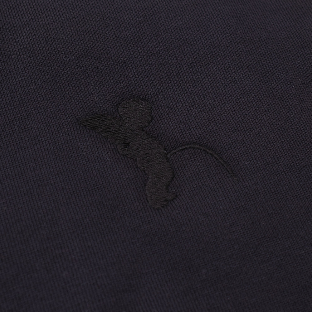 Macro studio perspective of the left chest on the black Token Grand Crewneck, detailing the subtle tonal black satin-stitch embroidery depicting the iconic Brussels Manneken Pis cherub statue motif directly on the smooth cotton sweatshirt surface.