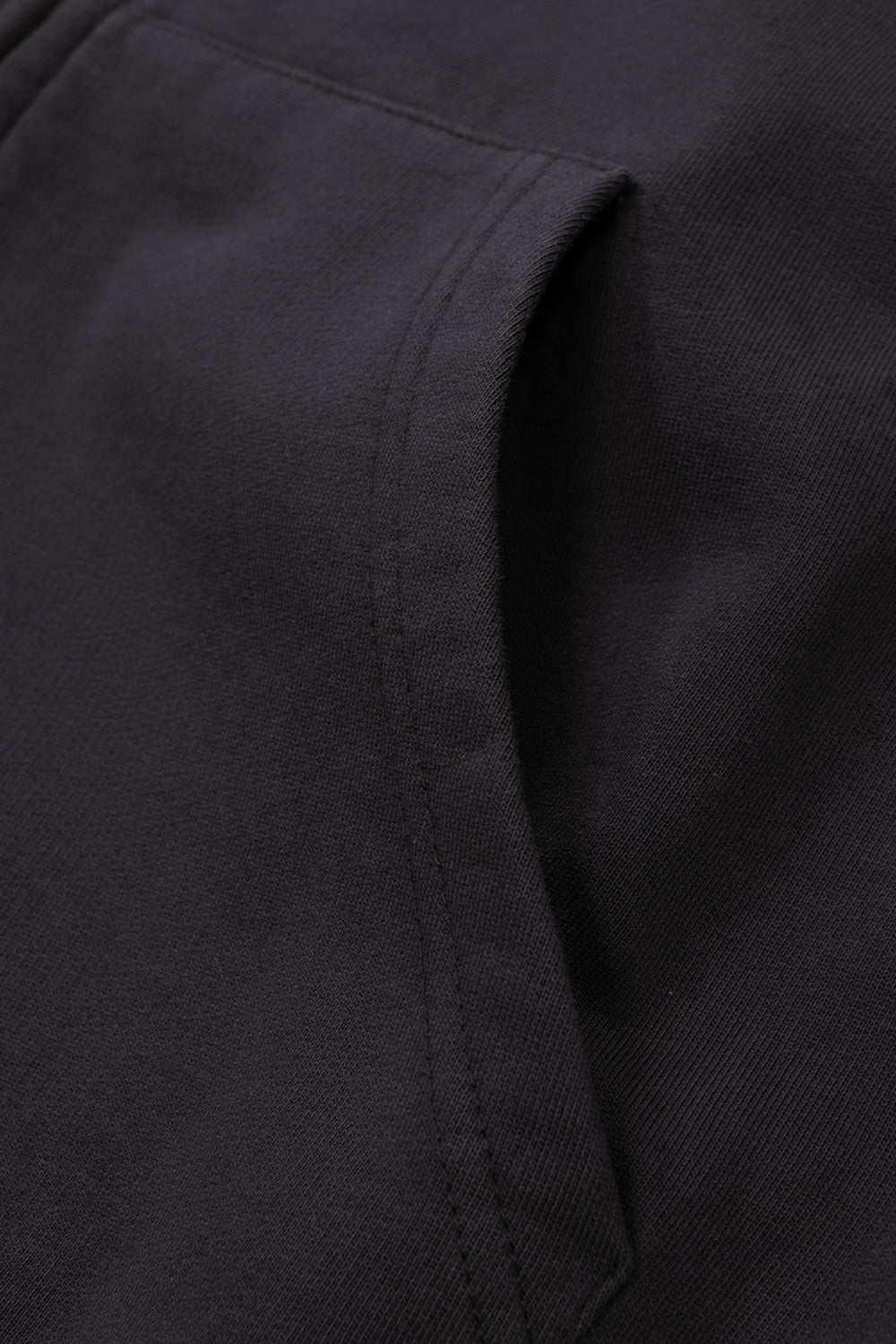 Studio close-up view of the split kangaroo front pocket on the washed black Umbro Authority Hoodie, detailing the curved reinforced pocket entry seam, heavy cotton fleece texture, and precise double-needle edge stitching