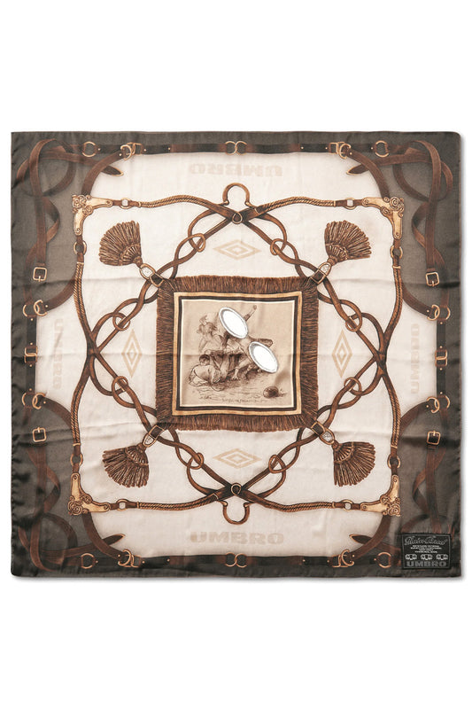 Full flat lay overview of the square Umbro Belt Masked Foulard measuring roughly 68 by 68 cm, crafted in Italy from 100% printed polyester fabric, displaying an intricate equestrian belt, stirrup, and tassel motif in olive, brown, and beige tones framing a central framed vintage football sketch with two embroidered oval eye slits and a woven black Umbro label in the bottom right corner
