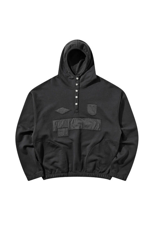 Front flat lay view of the Umbro Censored Pearls Hoodie in washed black, featuring a wide boxy cut, elasticated waistband and cuffs, a high neck hood with a five-button front placket adorned with pearl buttons, side pockets, and raw-edged tonal black jersey patches covering the chest logo and sponsor area with exposed zig-zag topstitching