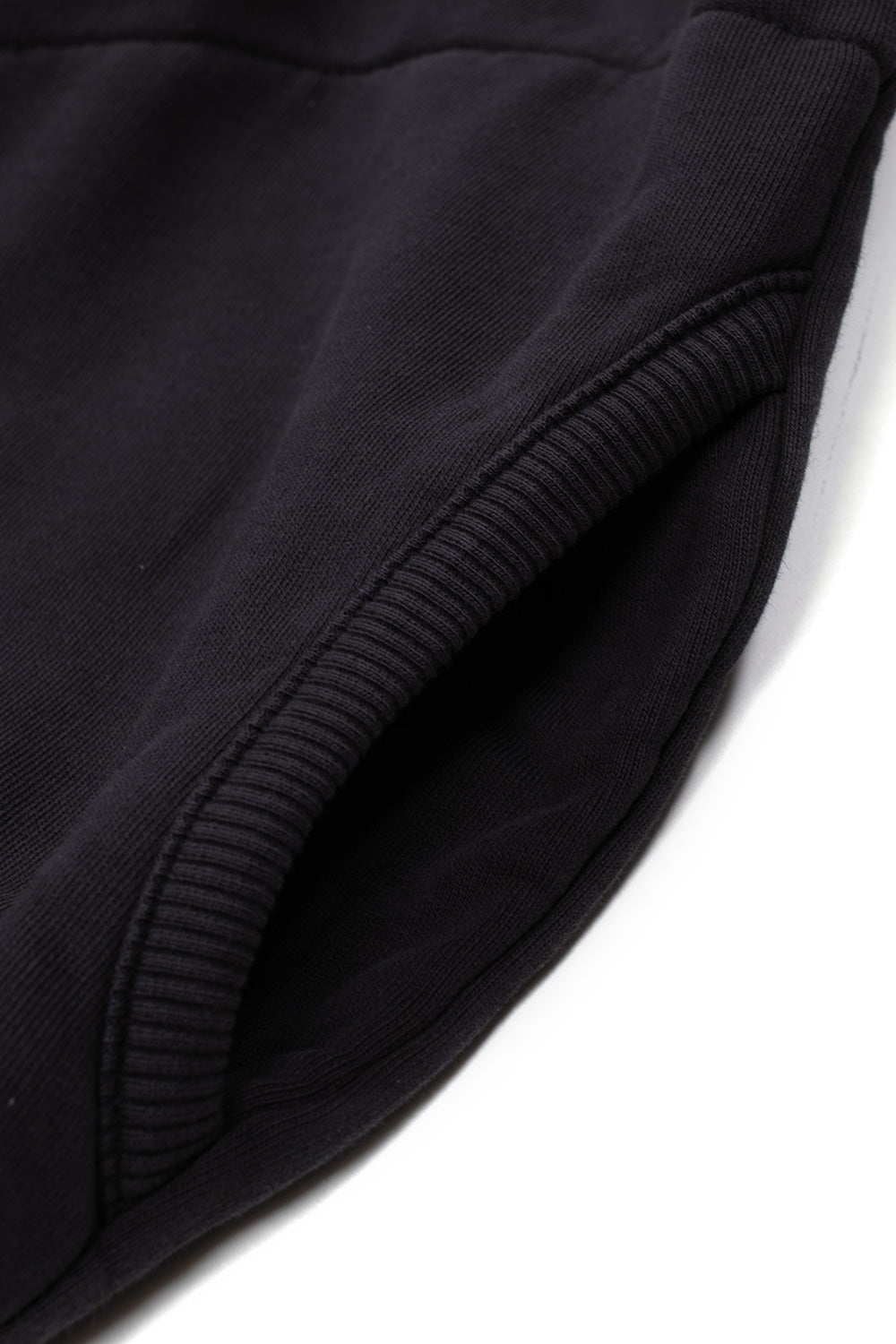 Studio close-up view of the side entry pocket on the washed black Umbro Censored Pearls Hoodie, detailing the curved ribbed knit welt pocket opening and the soft faded cotton fleece fabric texture