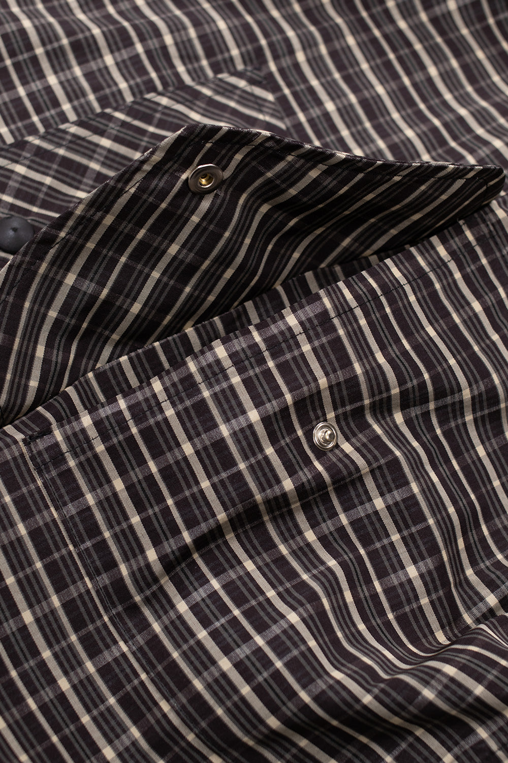 Macro shot of front flap pocket with snap closure on Umbro beige dark brown check anorak jacket, functional streetwear outerwear