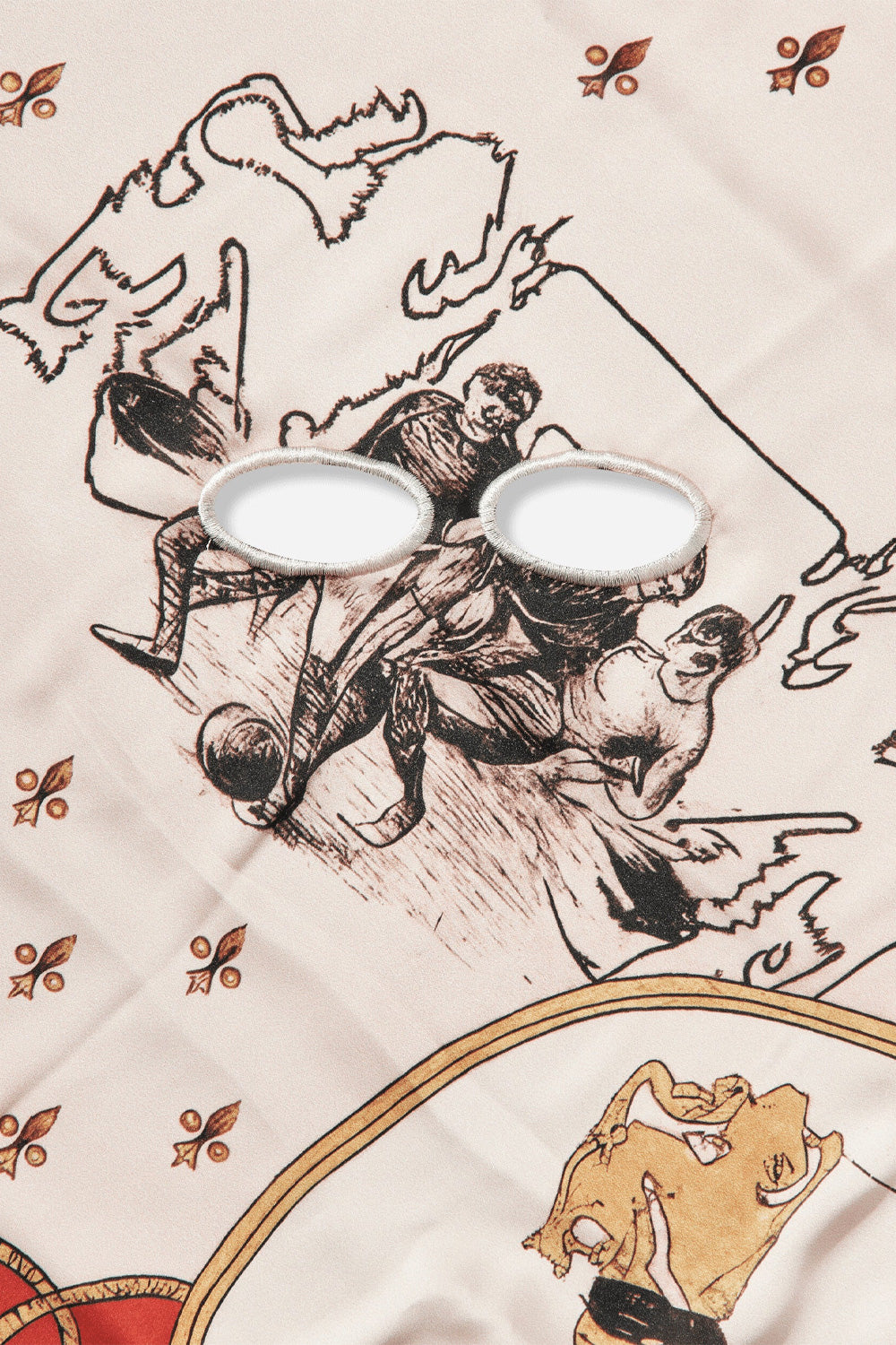 Detailed close-up shot of the central illustration on the Umbro Crest Masked Foulard, showing two oval cutout eye holes finished with dense cream satin-stitched embroidery, positioned directly over an antique sketch of vintage footballers contesting a leather ball on silky off-white fabric