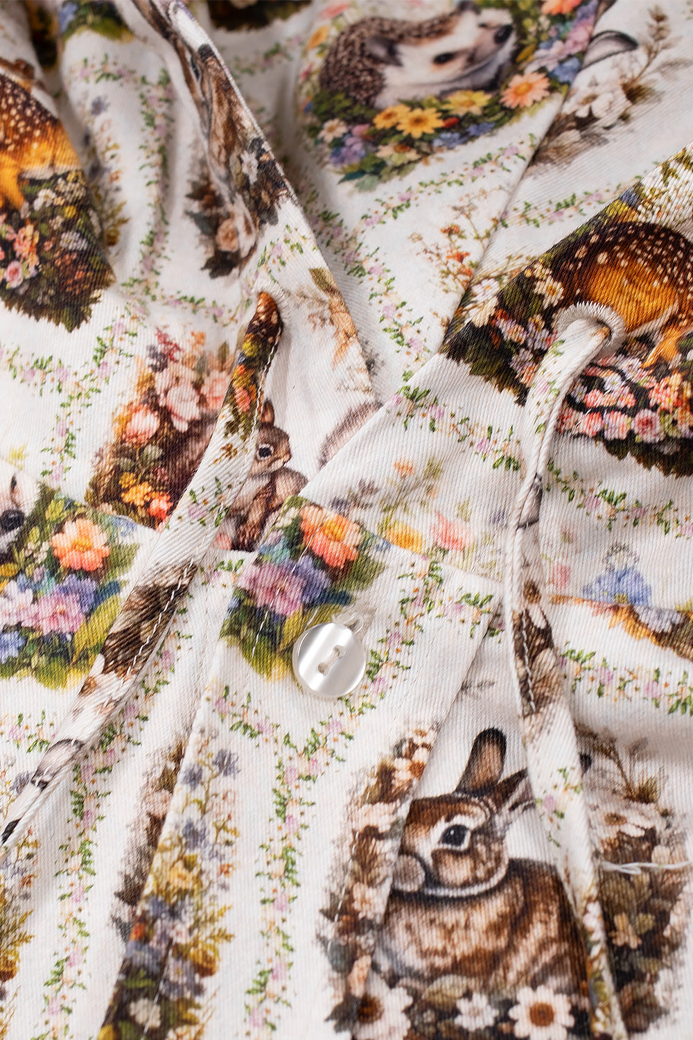 Close-up shot of the front neckline on the Umbro Cub Masked Shirt, highlighting the matching printed drawstrings, pearlized white buttons along the placket, and the detailed woven tapestry print featuring brown hares and hedgehogs nestled in wildflowers