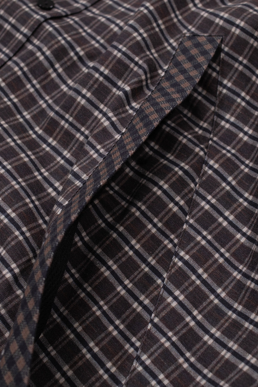 Close-up view of the slanted side entry pocket on the Umbro Double Plaid Jacket, showing the subtle contrast trim along the welt opening and the intersecting woven lines of the dark brown plaid fabric