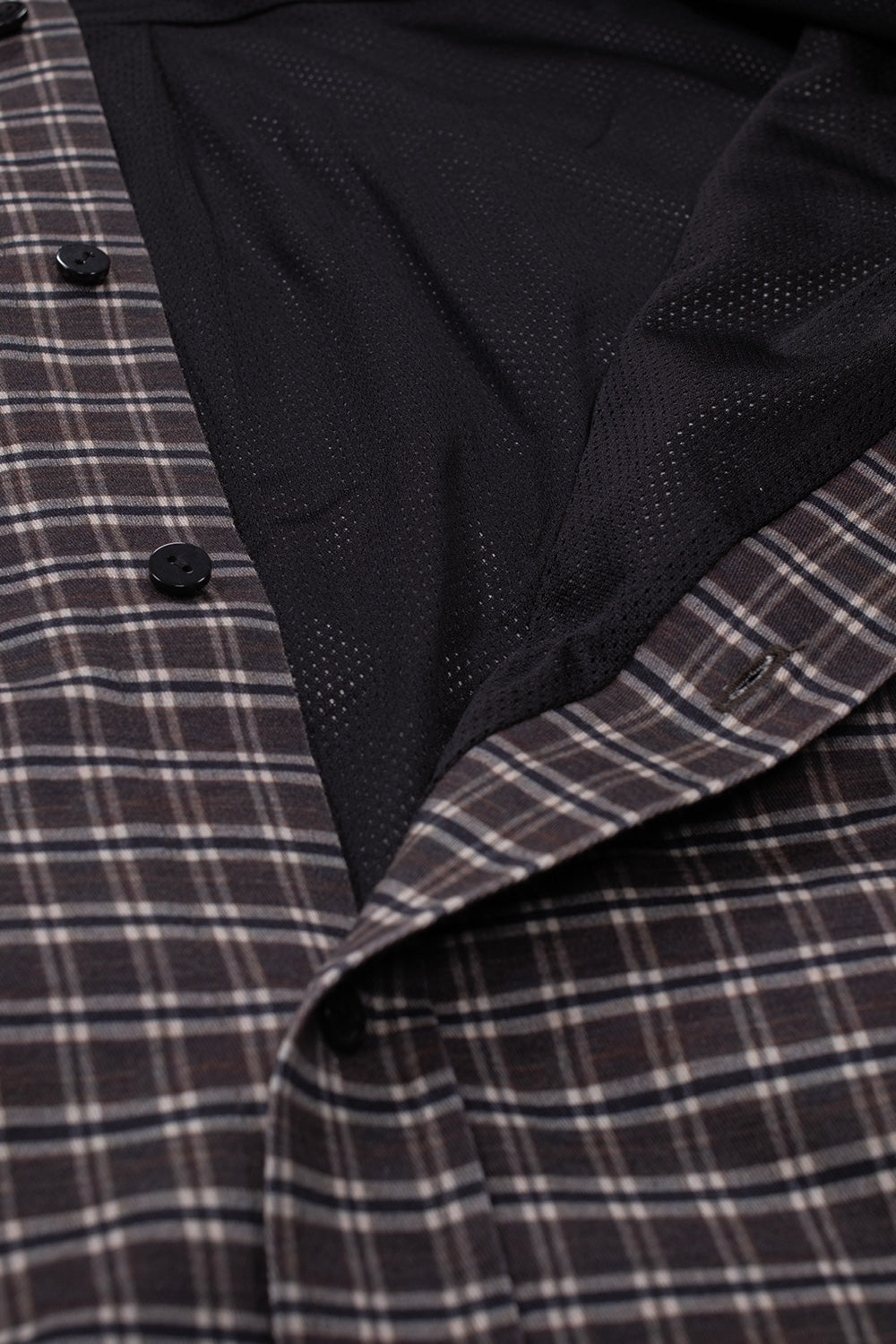 Macro studio perspective of the opened front placket on the Umbro Double Plaid Jacket, revealing the breathable black athletic mesh interior lining, button closures, and neatly finished inner seams