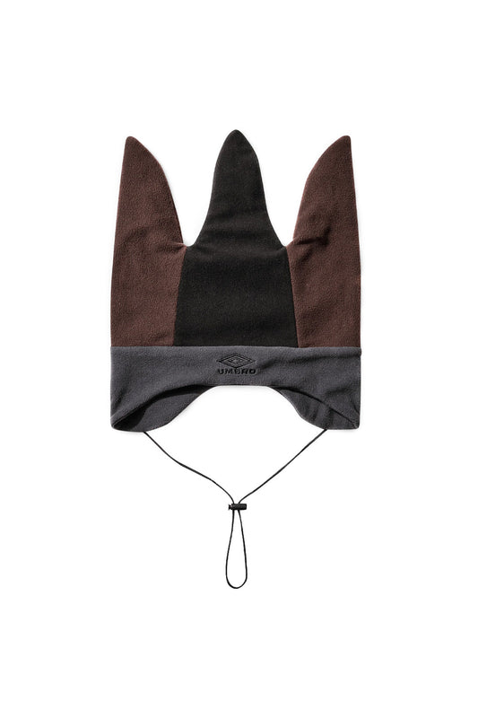 Front flat lay view of the Umbro Fleece Jester Hat in Burgundy, Charcoal, and Black, crafted from soft 100% polyester thermal fleece, featuring a color-blocked three-pointed jester crown with brown-burgundy outer peaks and a black center panel, an earflap-shaped charcoal grey fleece band, black embroidered Umbro double diamond logo lettering, and a thin black chin drawstring with an adjustable toggle stopper