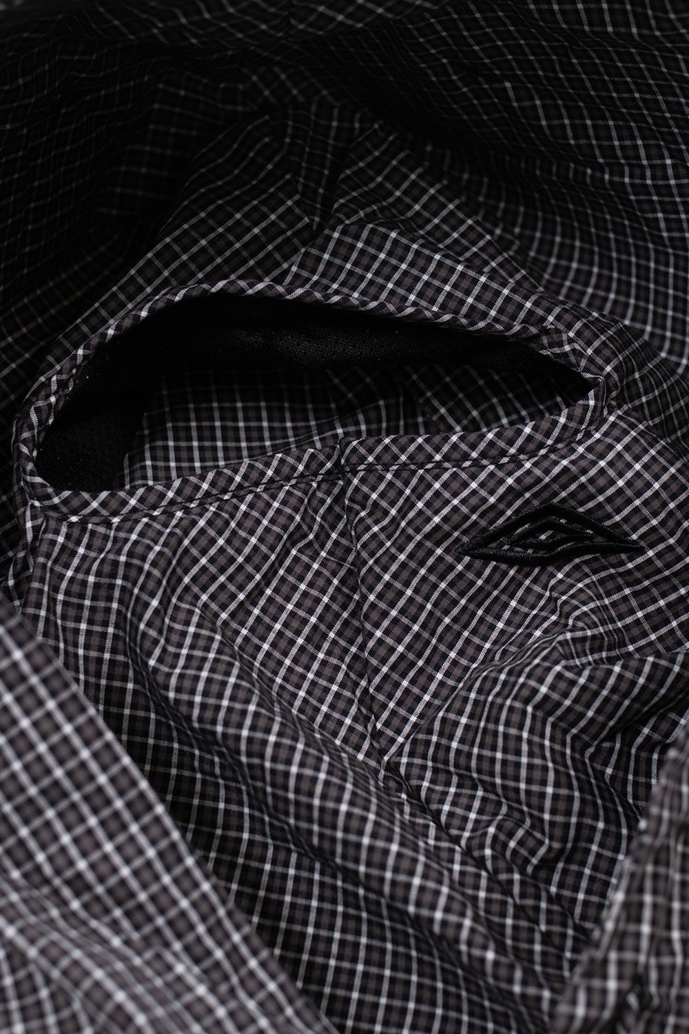 Detail shot of the integrated mask and drawstring hood on the Umbro Gingham Masked Shirt, combining functional sportswear elements with progressive street fashion aesthetics.