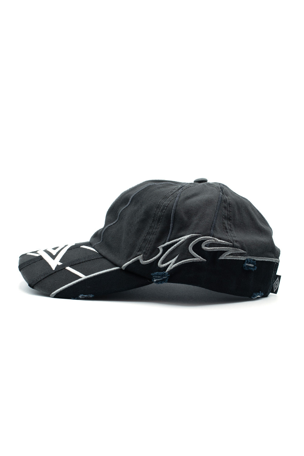 Left profile studio shot of the Umbro Goalkeeper Cap, displaying the low-profile 6-panel fit, curved brim with dimensional layered threadwork, distressed fraying along the lower edge, and dynamic silver-grey tribal flame embroidery extending along the side crown
