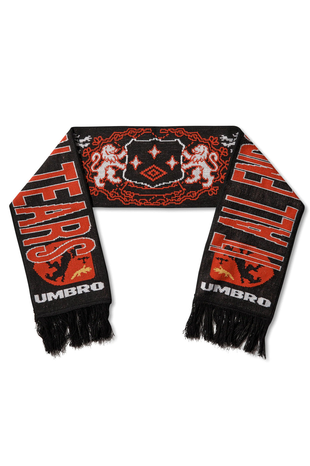 Reverse flat lay view of the Umbro It All Ends In Tears Scarf, highlighting the bold red and white outlined typography reading "IT ALL ENDS IN TEARS" framed by white Umbro wordmark branding above black fringe tassels, alongside a central red-and-white heraldic crest featuring twin supporters flanking a diamond shield on black knit fabric