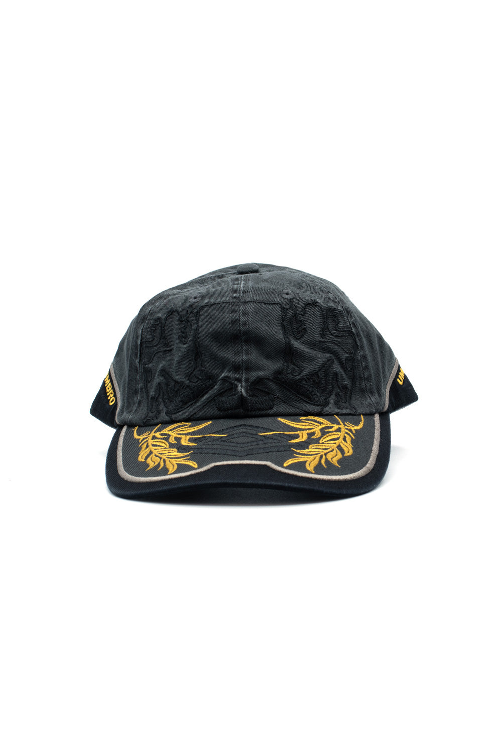 Front studio portrait of the Umbro Laurel Cap in washed dark green cotton, showcasing a 6-panel construction with tonal heraldic lion crest embroidery across the front crown, yellow Umbro side branding, and a curved black brim adorned with vibrant golden-yellow laurel wreath embroidery encircling a tonal black double diamond emblem
