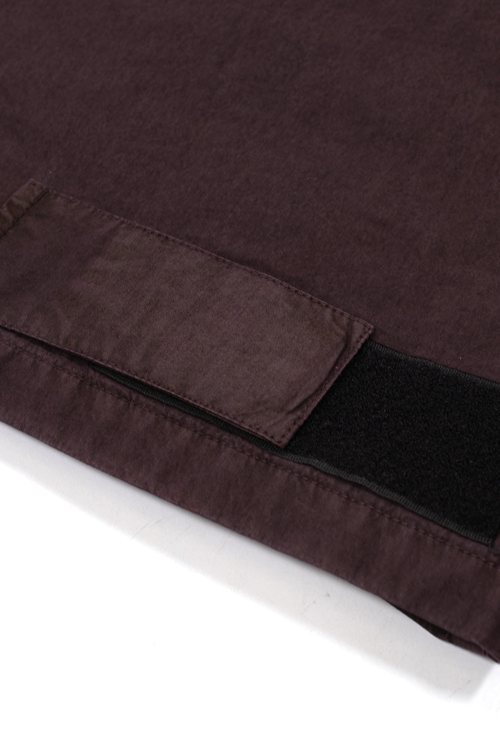 Close-up view of the lower hem cinch adjustment on the Umbro Midfield Jacket, displaying a fabric cinch tab overlaying a wide black hook-and-loop velcro strip along the bottom seam of the jacket