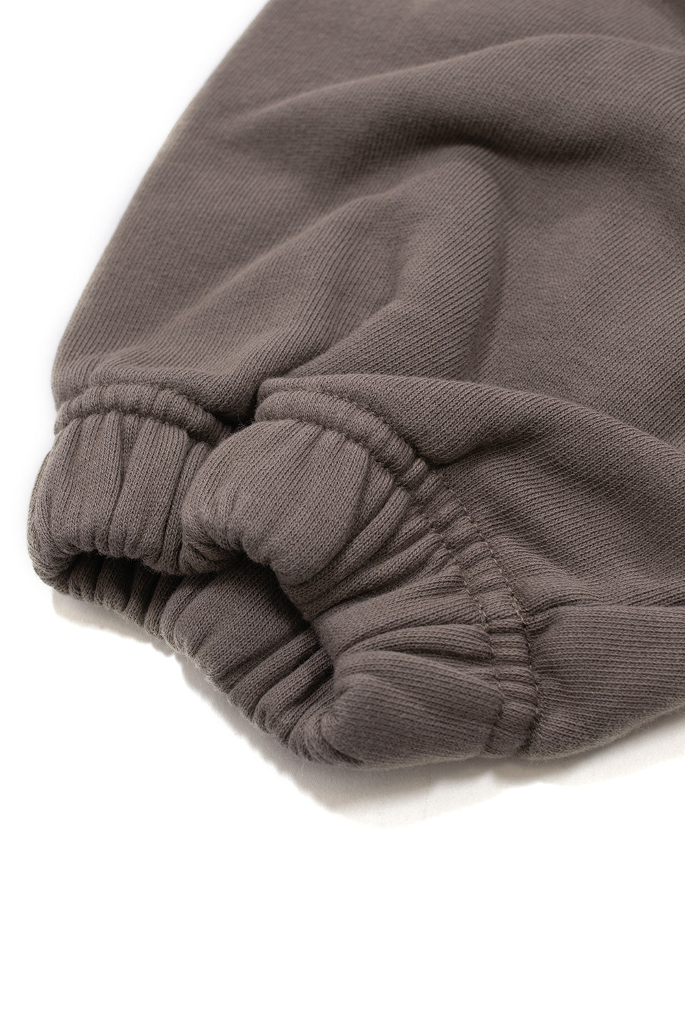 Macro detail of the gathered elastic sleeve cuff on the Umbro OG Logo Mask Hoodie in dark greige, highlighting the ruched shirred stretch stitching and the soft-washed finish of the heavy cotton sweatshirt fabric