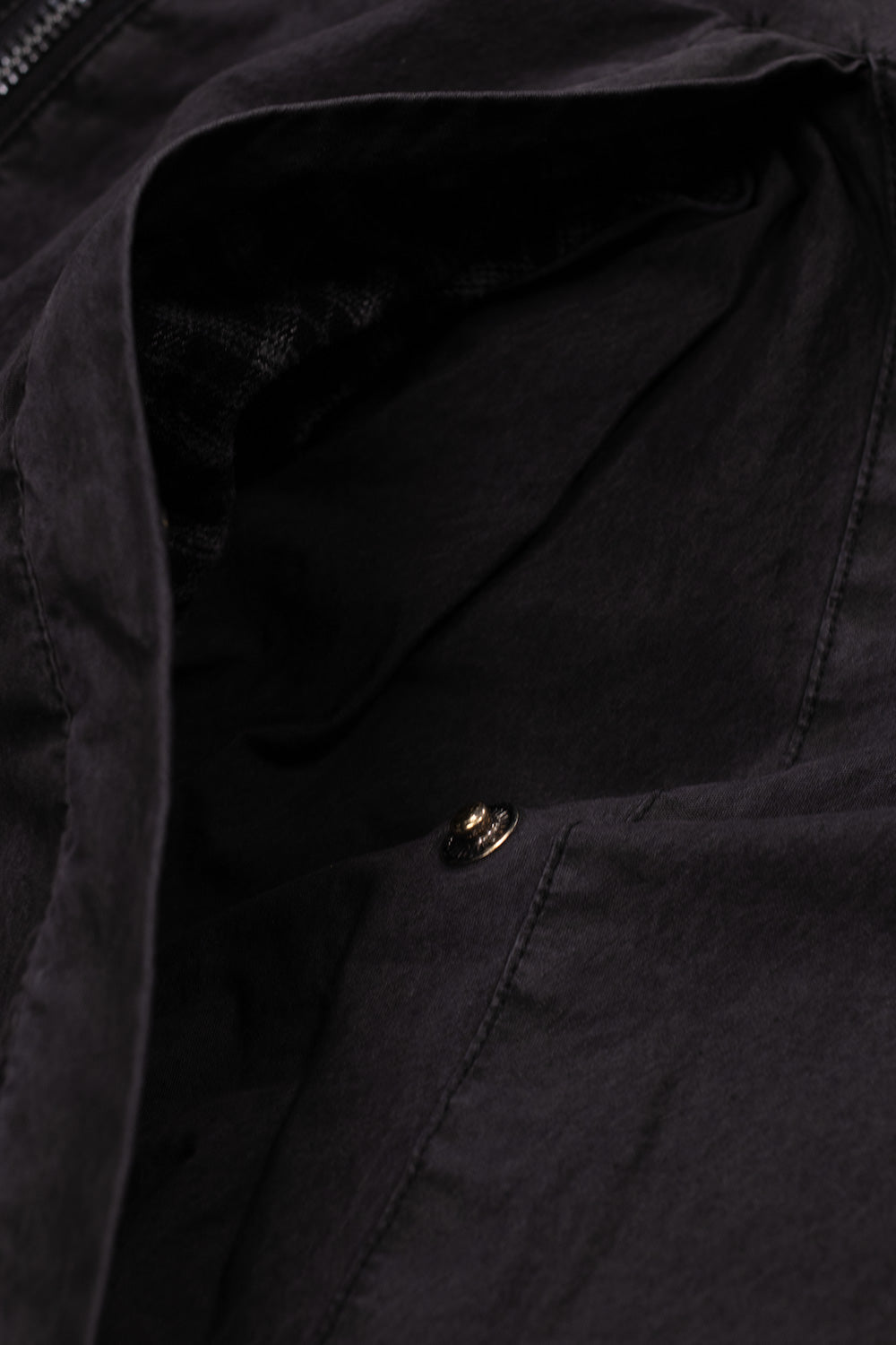 Close-up shot of the slanted side entry pocket on the Umbro Sunday Masked Jacket, showing the metallic engraved snap button fastener, reinforced welt seam stitching, and the internal dark plaid check lining