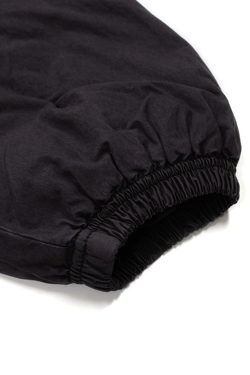 Macro detail of the gathered elastic sleeve cuff on the washed black Umbro Sunday Masked Jacket, highlighting the dense gathered stitching and the textured soft-washed cotton surface
