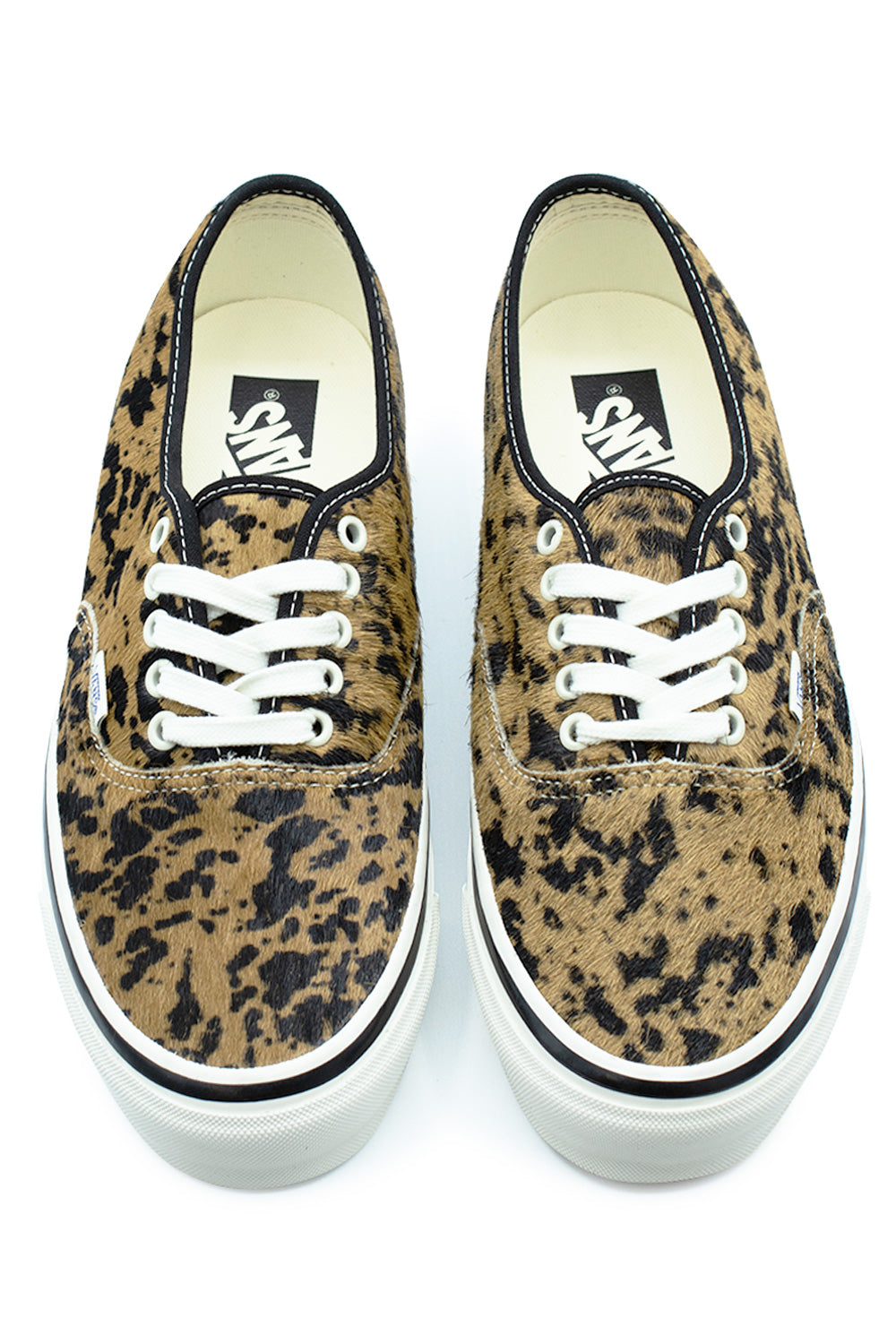 Top-down perspective of a pair of Vans LX Authentic 44 low-top shoes in Cow Marshmallow, highlighting the wild animal-patterned pony hair toe box and vamp, clean white eyelets with flat white laces, and cream interior footbeds printed with black Vans logos.