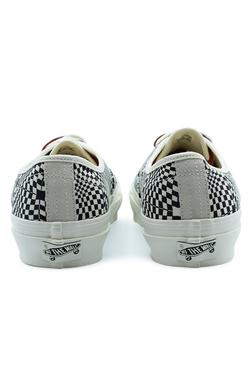 Rear view of the heels of the Vans LX Authentic 44 Heritage Black sneakers, featuring light grey suede heel strips over the distorted checkerboard canvas upper and the retro black-and-white Off The Wall license plate patch on the off-white midsole.