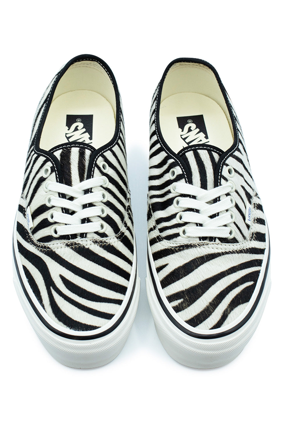 Top-down view of a pair of Vans LX Authentic 44 low-top shoes in Zebra Marshmallow, highlighting the wild zebra-striped pony hair vamp and toe box, white eyelets with flat white cotton laces, and cream footbeds printed with black vintage Vans logos.